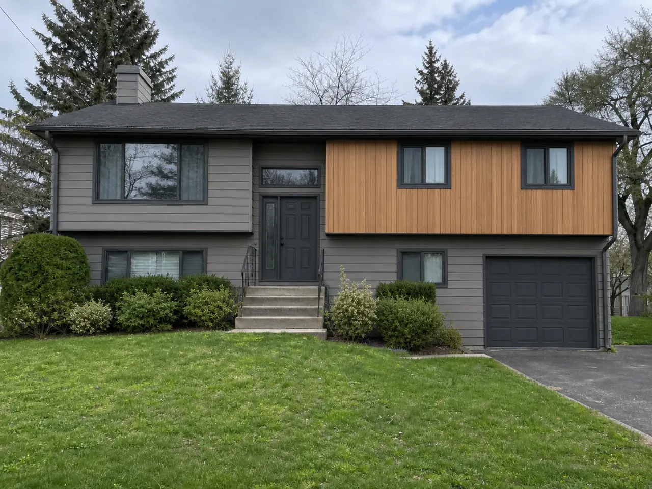 The same split-level house with gray fiber-cement siding and cedar accents